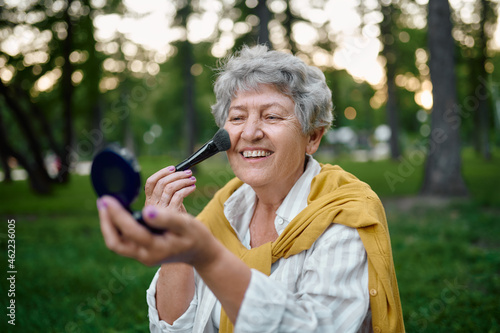 Pretty granny does makeup in park, back to yout photo