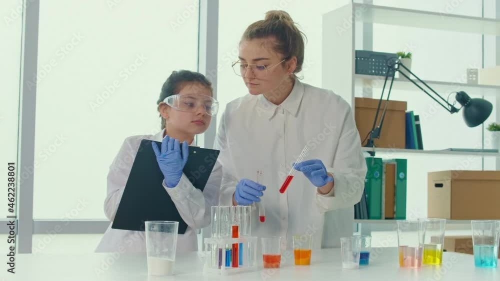 A Teenage Girl With a Teacher in Lab Coats and Safety Glasses Conducts ...