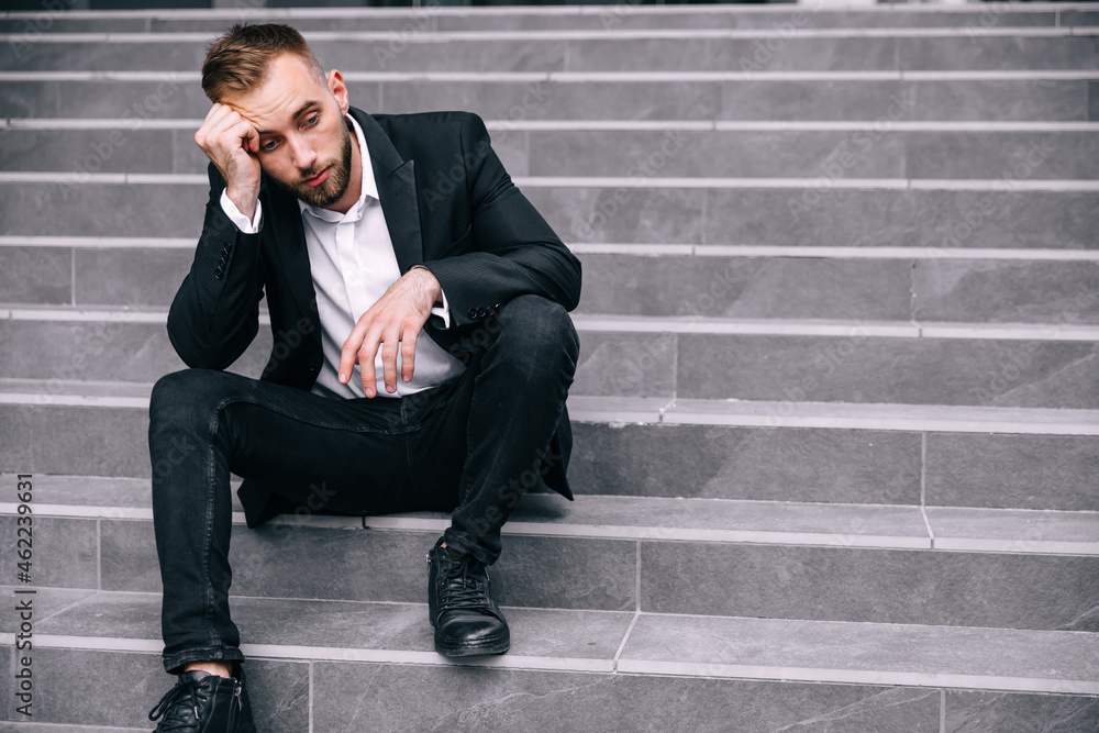 businessman in formal clothes sitting on the street stairs worried about the problem at work. businessman in formal clothes sitting on the street stairs worried about the problem at work.