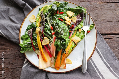 Wilted swiss chard salad with butter and garlic on rustic table photo