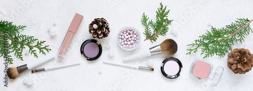 Decorative cosmetic products and Christmas decorations on white stone background close up. Christmas cosmetic sale and promo banner.