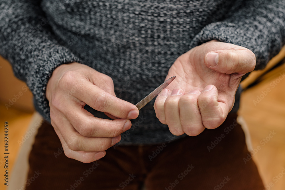 Closeup photo of man doing manicure himself at home, male self-care
