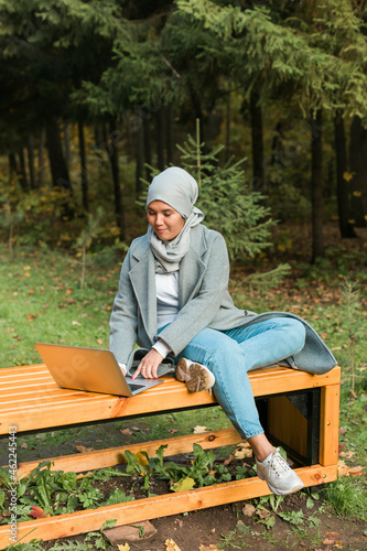 Muslim woman with her laptop in the park.