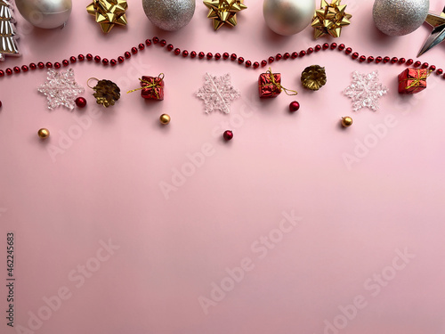 Christmas decorations, gift box ribbons, golden balls, snowflakes, red balls on pink background