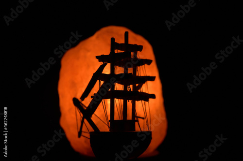 Silhouette of the model copy of a fregate in the glare of the salt stone lantern photo