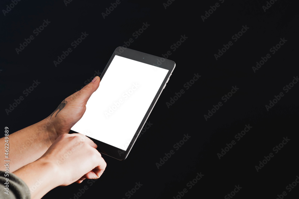 Tätowierte Hand mit Tablet auf dunklem Hintergrund Tätowierte Hand mit Tablet auf dunklem Hintergrund