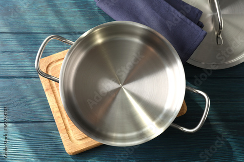 Empty metal pot on cutting board on wooden table