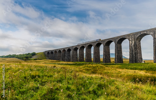 A view of a train on the middle of the Ribblehead Viaduct, Yorkshire, UK in summertime photo