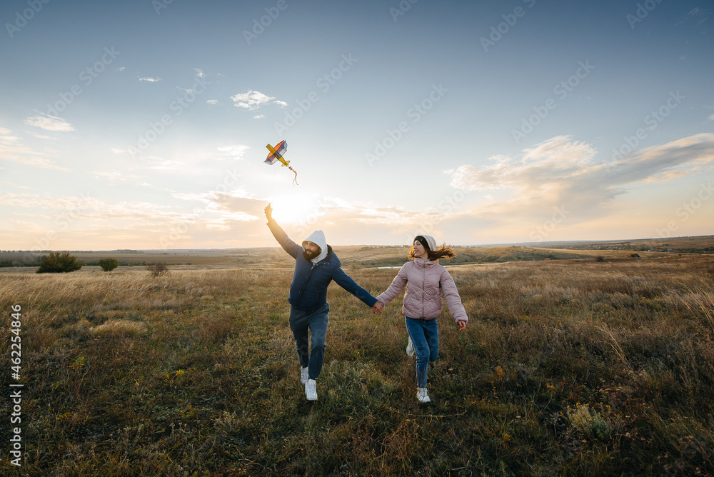 A happy couple flies a kite and spends time together in the fresh air. Happy relationship and family vacation. A happy couple flies a kite and spends time together in the fresh air. Happy relationship and family vacation.