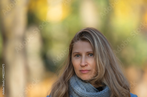 Portrait of a beautiful young blonde girl in a blue coat in an autumn park, close-up.