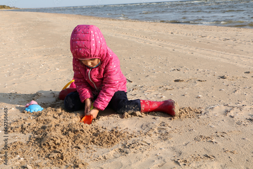 Girl playing in the sand on the beach in autumn. Girl playing in the sand on the beach in autumn.