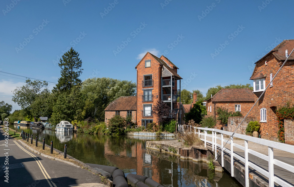 Fototapeta premium Newbury, Berkshire, England, UK. 2021. White wooden swing bridge over the Kennet and Avon Canal at Newbury, tall buildings a former granary. UK