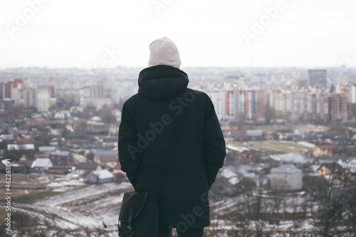 guy with shopping bag looking at city panorama in winter season