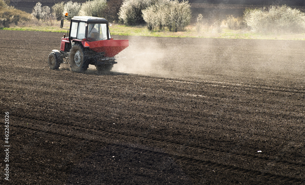 Fototapeta premium Tractor spreading artificial fertilizers in field