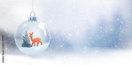 Gläserne Weihnachtskugel vor unscharfem Blauem Hintergrund mit Schneeflocken
