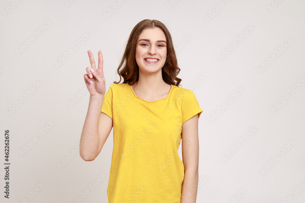 Φωτογραφία Beautiful satisfied teenager girl showing v sign symbol of peace with fingers, looking at camera with happy smile, celebrating triumph