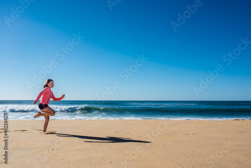 cute young girl running and jumping on sunny beach