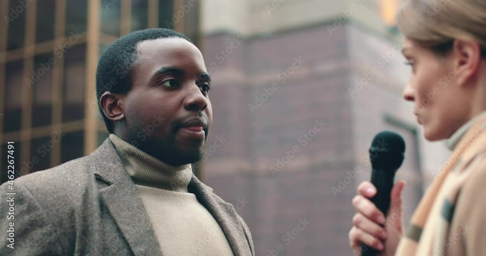Close up of successful african american businessman standing on street and giving interview to reporter answering questions in microwave.