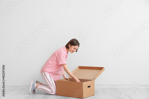 Young woman with wardrobe box near light wall