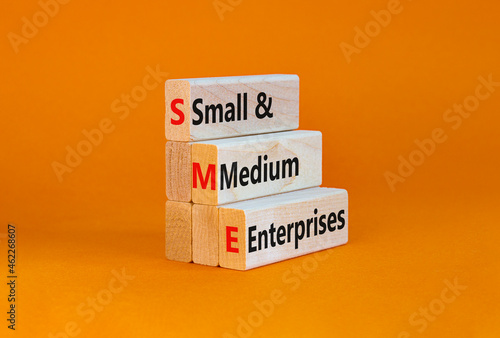 SME small and medium enterprises symbol. Words SME small and medium enterprises on blocks on a beautiful orange background. Business and SME small and medium enterprises concept. Copy space. photo