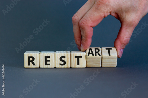 Rest and restart symbol. Businessman turns wooden cubes and changes the word 'rest' to 'restart'. Beautiful grey background, copy space. Business, rest and restart concept.