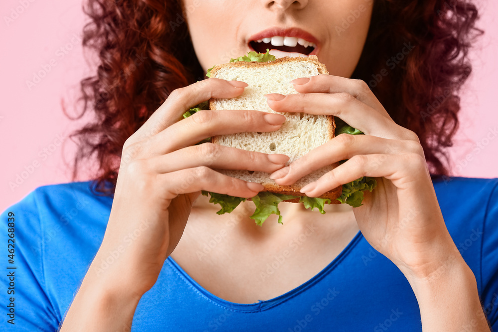 Young woman eating tasty sandwich on pink background, closeup Young woman eating tasty sandwich on pink background, closeup
