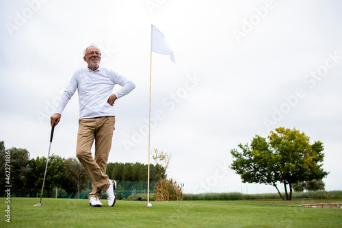 Фотография Portrait of an active senior man playing golf at the golf course and enjoying free time outdoors
