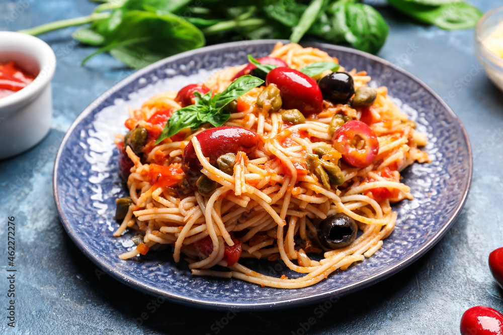 Plate of tasty Pasta Puttanesca on blue background