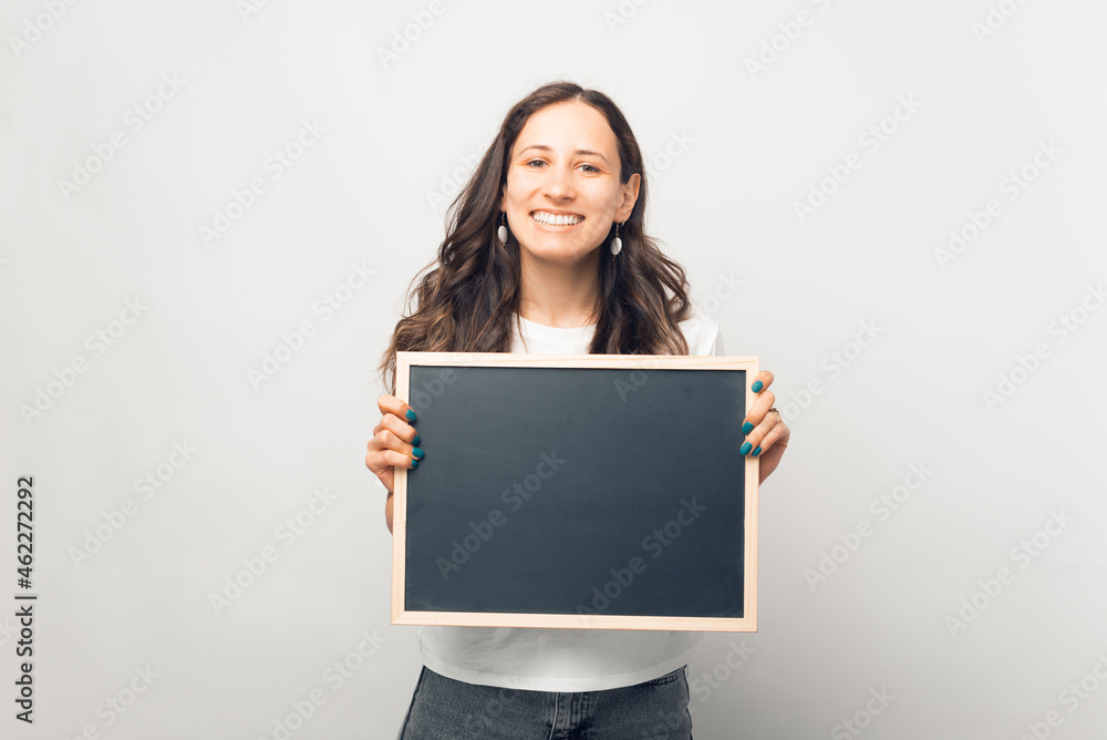 Smiling woman is holding a small blackboard with space for your text. Smiling woman is holding a small blackboard with space for your text.