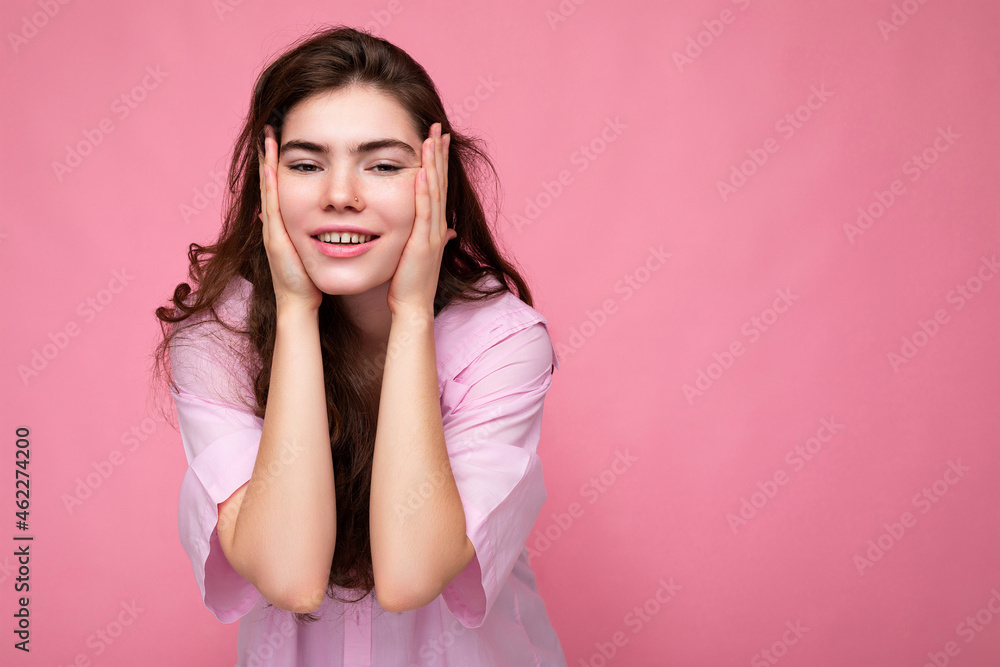 Photo of young beautiful happy smiling curly brunette woman wearing pink shirt. Sexy carefree female person posing isolated near pink wall in studio with free space. Positive model with natural makeup Photo of young beautiful happy smiling curly brunette woman wearing pink shirt. Sexy carefree female person posing isolated near pink wall in studio with free space. Positive model with natural makeup