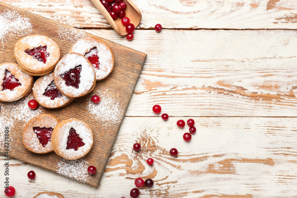 Board with tasty Linzer cookies, cranberry and powdered sugar on table