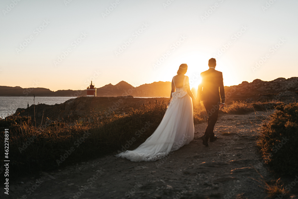 Just married couple walking towards a lighthouse