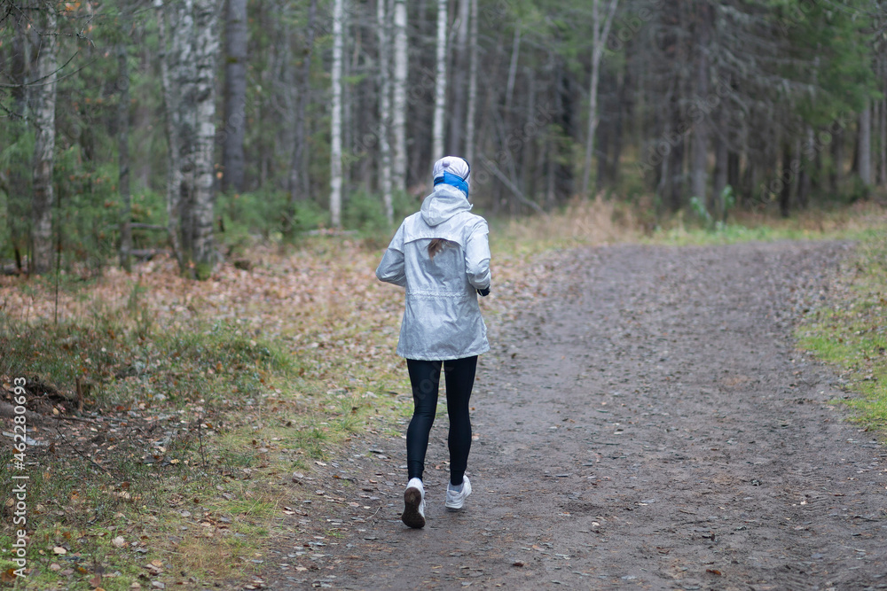 Fototapeta premium A woman is running in the forest, in the park.Fitness on the street.