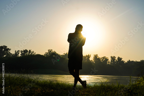 silhouette of a boy in park near sun and river - health concept photo