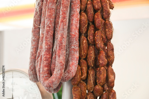 There are two types of meat sausages hanging next to the scales