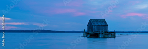 Panorama of an old fishing hut at Blue Rocks, Nova Scotia during Blue Hour with pink sunset clouds at high tide photo