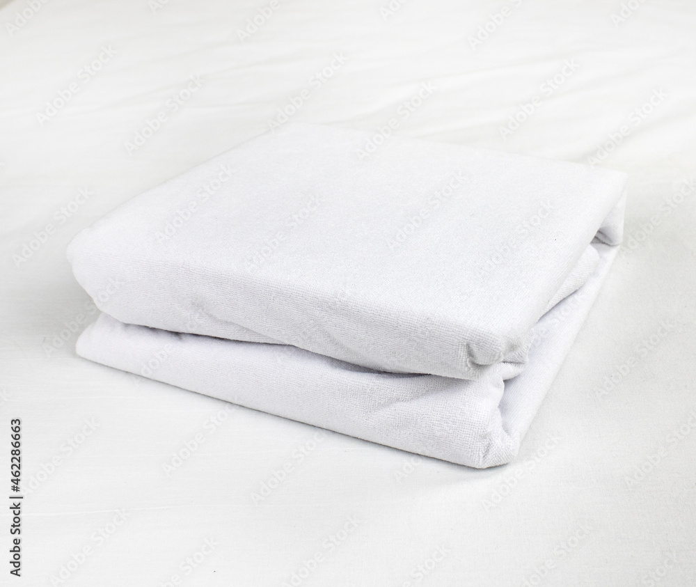 White, neatly folded terry waterproof mattress topper. Mattress covers. Protection of the bed from water and baby secretions. Production of mattress covers from cotton materials White, neatly folded terry waterproof mattress topper. Mattress covers. Protection of the bed from water and baby secretions. Production of mattress covers from cotton materials