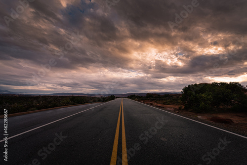фотографія Long desolate desert road in the middle of nowhere under dramatic stormy sunrise