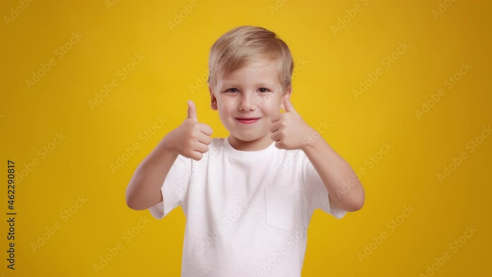 Kids approval. Studio portrait of cute little caucasian boy gesturing thumbs up with both hands and smiling to camera Kids approval. Studio portrait of cute little caucasian boy gesturing thumbs up with both hands and smiling to camera