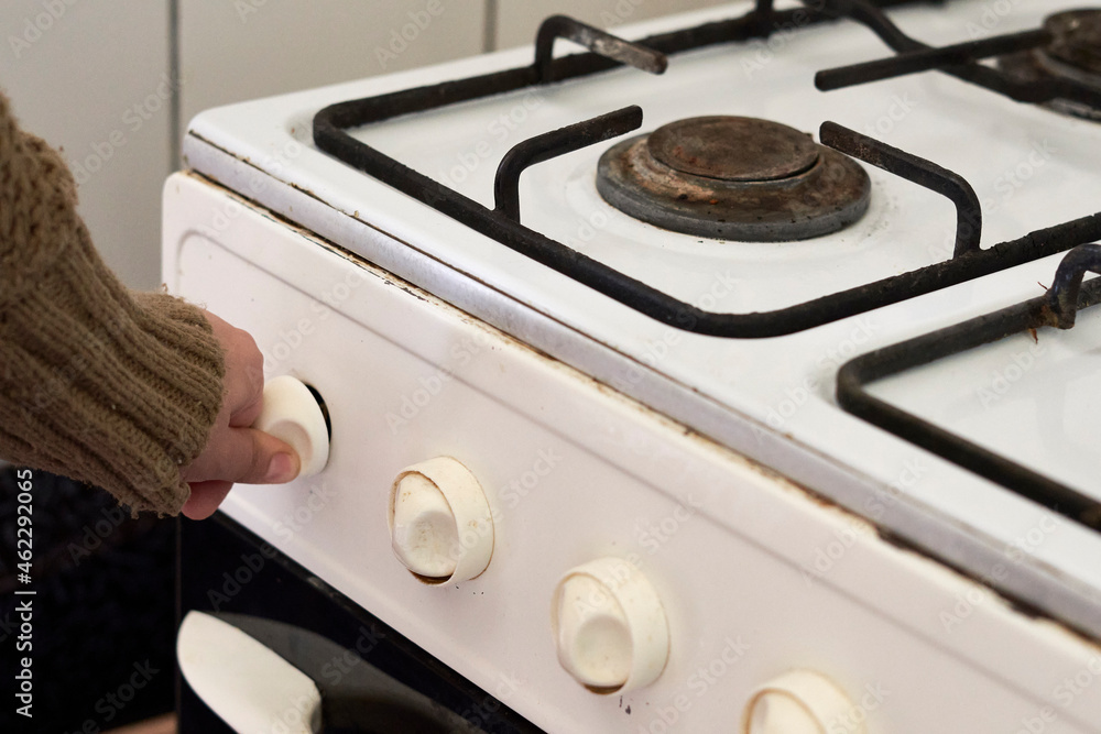 Woman checking gas. Female hand trying to turn on old gas stove. No gas, Winter and cold period concepts. Lack of gas in the pipeline Woman checking gas. Female hand trying to turn on old gas stove. No gas, Winter and cold period concepts. Lack of gas in the pipeline