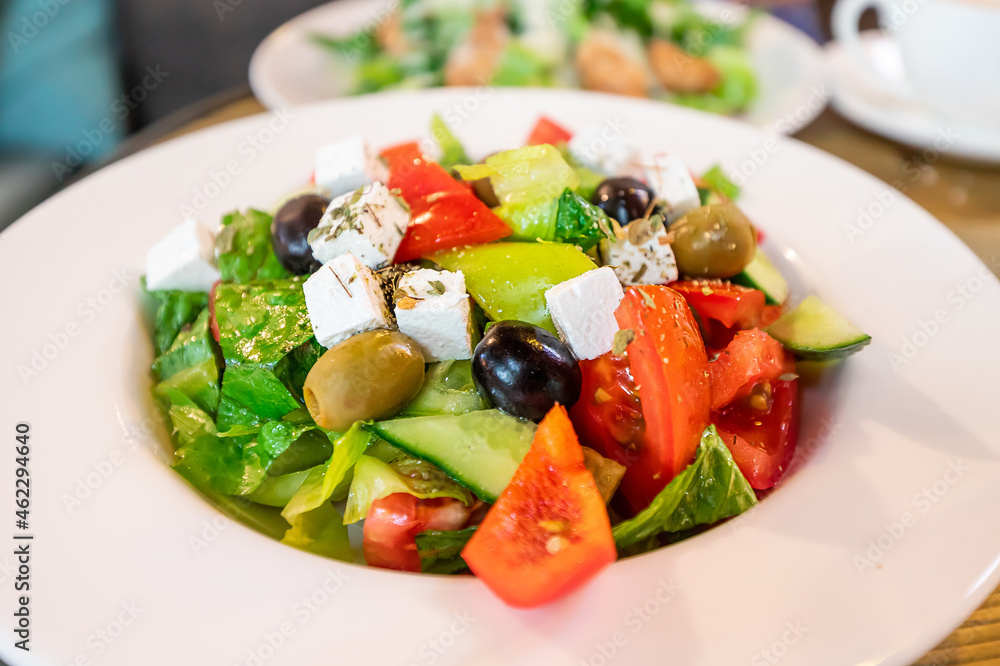 Greek salad with feta cheese and olives on a plate in a cafe as a symbol of Mediterranean cuisine and diet Greek salad with feta cheese and olives on a plate in a cafe as a symbol of Mediterranean cuisine and diet