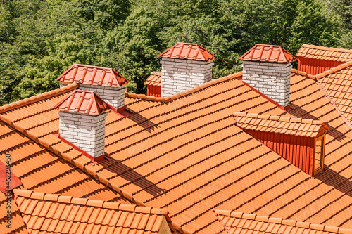 Orange roof of a modern house is covered with orange tiles. chimneys and attics in a residential building