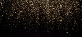 Gold glitter texture on black. Shinny small particles reflecting light.