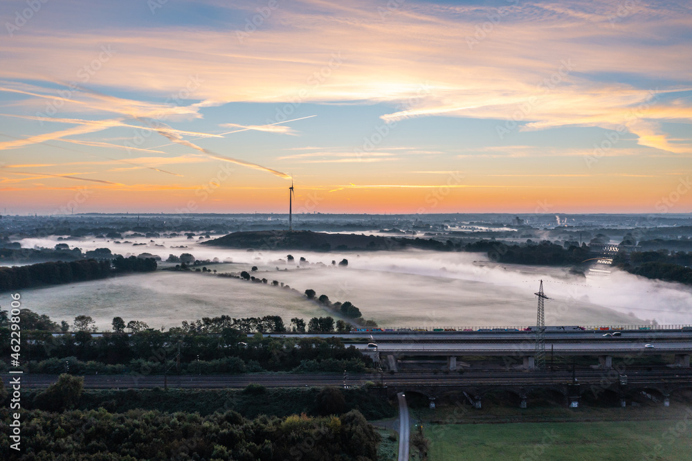Sunrise and the first rays of sunshine over the fog-covered Ruhr meadows in Duisburg, Germany