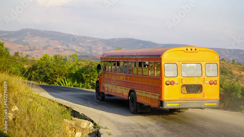 Yellow school bus driving on a serpentine road in the mountains photo