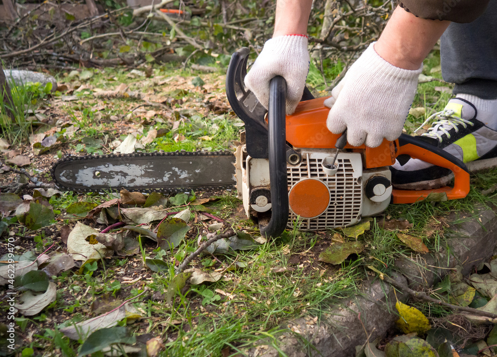 Obraz premium a man's hands start a chainsaw in the garden