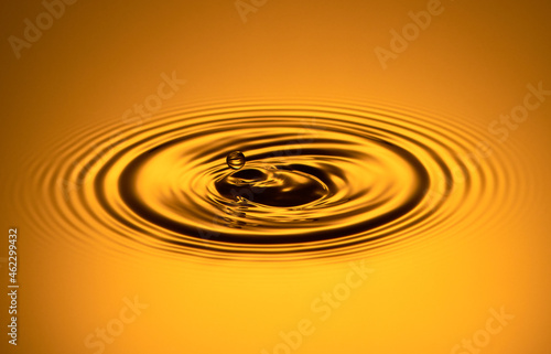 A drop of water in the air on a gold background.