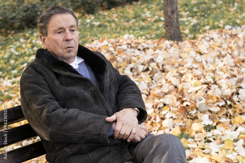 A lonely senior man sitting on the bench in park A lonely senior man sitting on the bench in park