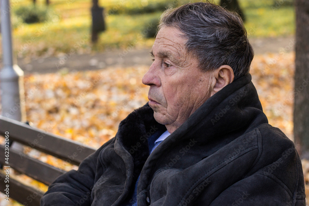 A lonely senior man sitting on the bench in park A lonely senior man sitting on the bench in park