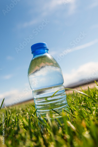 Bild auf Leinwand Small bottle of mineral water on trimmed grass